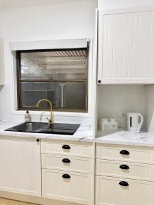 a white kitchen with a sink and a window at Ferguson House in Cessnock +35 photos