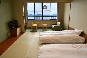a hotel room with two beds and a table and chairs at Sapporo's Secret Onsen Sanctuary Marukoma Onsen Ryokan in Chitose