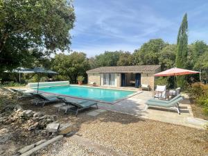 a swimming pool with chairs and a house at Lou Mas in Gordes