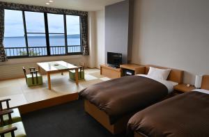 a bedroom with two beds and a table and a window at Sapporo's Secret Onsen Sanctuary Marukoma Onsen Ryokan in Chitose
