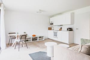 a white living room with a table and a kitchen at Les Joyaux d'Eliane in Le Bernard