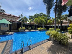 a large swimming pool with palm trees and a building at JKAB Park Hotel in Trincomalee