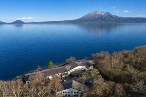 an aerial view of a house on the shore of a lake at Sapporo's Secret Onsen Sanctuary Marukoma Onsen Ryokan in Chitose