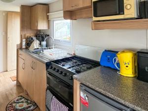 a kitchen with a stove and a microwave at Joys in Jaywick Sands