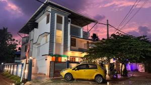 a yellow car parked in front of a house at Souparnika apartments in Varkala
