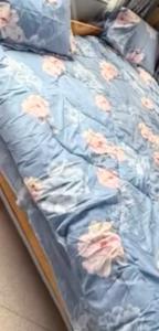 a bed with a blue blanket with flowers on it at Bibi Cosy Cottage in Moshi