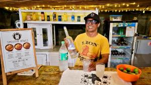 a man sitting at a table holding a bottle of water at Blind Dog Inn in Sanur