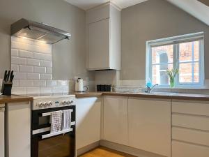 a kitchen with white cabinets and a stove top oven at Victoria Apartment 1 in Tarporley