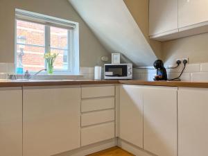 a kitchen with white cabinets and a window at Victoria Apartment 1 in Tarporley