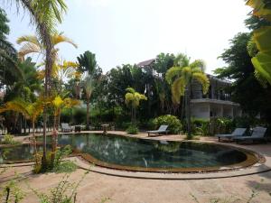 a pool in a yard with palm trees and a building at STC Hotel School in Phumĭ Réach Born (1)