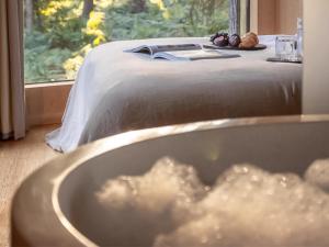 a bathroom with a bed with a tub and a window at Kanna-Qu7625 in Chipping Norton