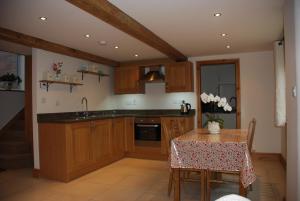 a kitchen with wooden cabinets and a table with a table cloth at Swallows Barn Cottage in North Rode