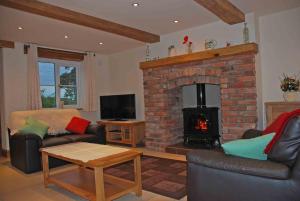 a living room with a fireplace and a couch and a table at Swallows Barn Cottage in North Rode