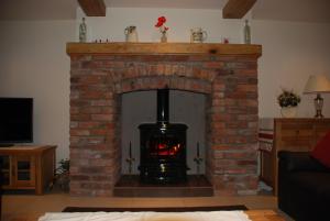 a brick fireplace with a fire in it at Swallows Barn Cottage in North Rode