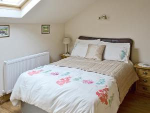 a bedroom with a bed with a floral bedspread at Swallows Barn Cottage in North Rode +7 photos