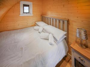 a bedroom with a bed with white pillows and a window at Katie's Pod in Acharacle