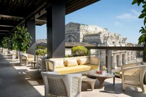 a patio with a couch and tables and chairs at Excelsior Hotel Gallia, a Luxury Collection Hotel, Milan in Milan