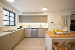 a kitchen with white cabinets and a bowl of fruit on a table at Carmelo I MOD Villa in Herzliya B