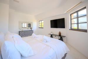 a white bedroom with a bed and a flat screen tv at Carmelo I MOD Villa in Herzliya B