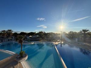 a large swimming pool with the sun in the sky at Le SaraLéna in Torreilles +11 photos
