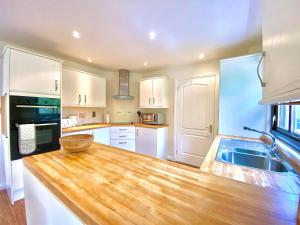 a kitchen with white cabinets and a wooden counter top at Lochindaal in Tarbert