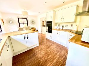 a large kitchen with white cabinets and wooden floors at Lochindaal in Tarbert