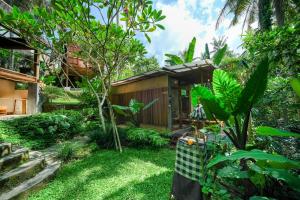 a garden with a small house in the background at Ubud Jungle Stay - Mahari by WAHM in Ubud