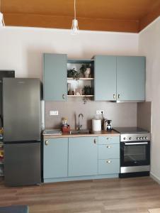 a kitchen with blue cabinets and a stainless steel refrigerator at Gaia in Posidhonía