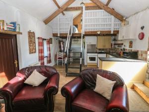 a living room with two leather chairs and a kitchen at Butterslade in Swansea