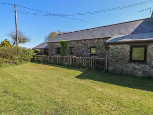 an old stone house with a fence in front of it at Butterslade in Swansea