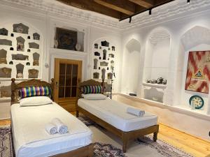 a bedroom with two beds and a wall with art at Barlos Boutique XVIII in Bukhara
