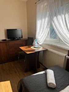 a bedroom with a table and a tv and a bed at Pokoje Hotelowe Wiktoria in Goczałkowice Dolne
