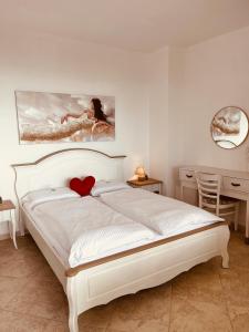 a bedroom with a white bed with a red heart on it at Panorama Pearl Sea View in Balchik +94 photos