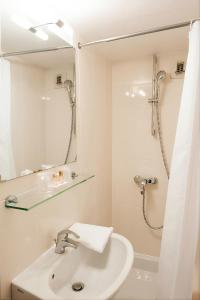 a white bathroom with a sink and a shower at Hotel de L'Opéra in Bordeaux
