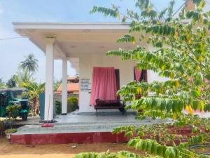 a small house with a pink curtain on the porch at MOMS Villa in Arugam Bay
