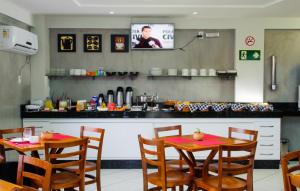 a restaurant with two tables and a kitchen with a tv at Caravelle Hotel in Guanhães