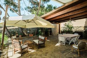 a patio with a table and chairs and an umbrella at Casa Levante - 3 camere, veranda e vista mare in Stintino