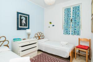 a bedroom with two beds and a dresser and a window at Casa Levante - 3 camere, veranda e vista mare in Stintino