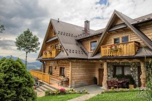 a large wooden house with a porch and a balcony at Noclegi u Gabrysi in Kościelisko