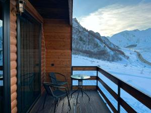 a balcony with a table and chairs and a view of the mountains at Eastlight Cottage in Gorists'ikhe