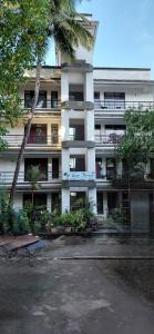 a white building with a palm tree in front of it at Hotel Wave Morjim in Morjim