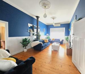 a living room with blue walls and wooden floors at Whispering Woods Pool Sauna in Maryborough
