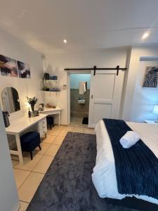 a bedroom with a bed and a desk and a bathroom at Cottage in Ballito in Ballito