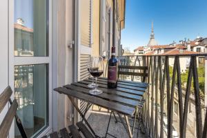 a wooden table with a glass of wine on a balcony at Le Monde Luxury Apartment in Turin