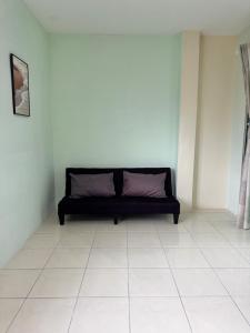 a black couch in a room with a tiled floor at Howie Home in Ipoh