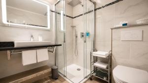 ein Badezimmer mit Dusche, Waschbecken und Toilette in der Unterkunft Hotel Seewisch in Flessenow
