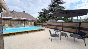 a patio with chairs and an umbrella and a pool at Chambres et Gîtes Les Deux Chênes près de Bergerac in Le Fleix