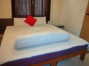 a bed with a red pillow on top of it at MVTJ Hotel in Bangalore