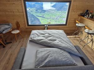a bed in a room with a large window at Seilbahnstubli in Ibergeregg
