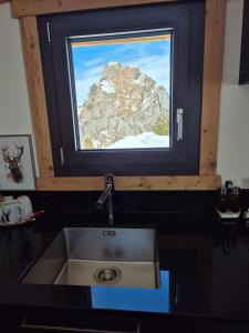 a sink in a kitchen with a view of a mountain at Seilbahnstubli in Ibergeregg +22 photos